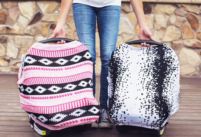 A Person Holding Two Cute Baby Carseats with Colorful Canopy Covers