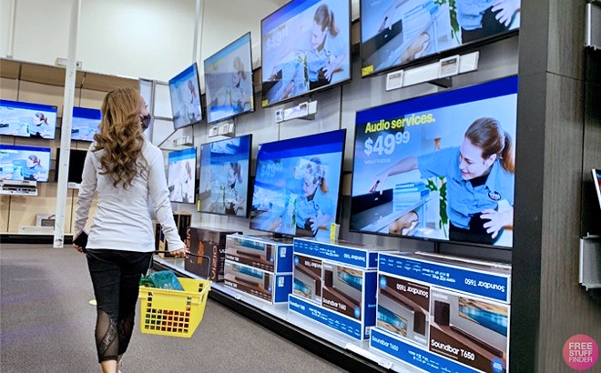 A Person Walking in a Store and Looking at TV Sets on Display