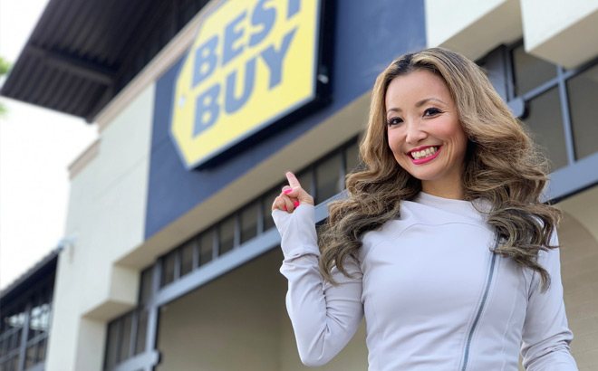 Woman Smiling and Standing In Front of a Best Buy Pointing to a Best Buy Store Sign in the Background