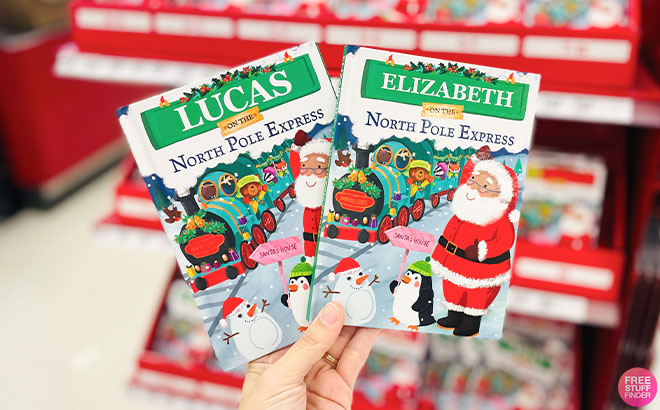 A Hand Holding a Two Pieces of North Pole Express Books