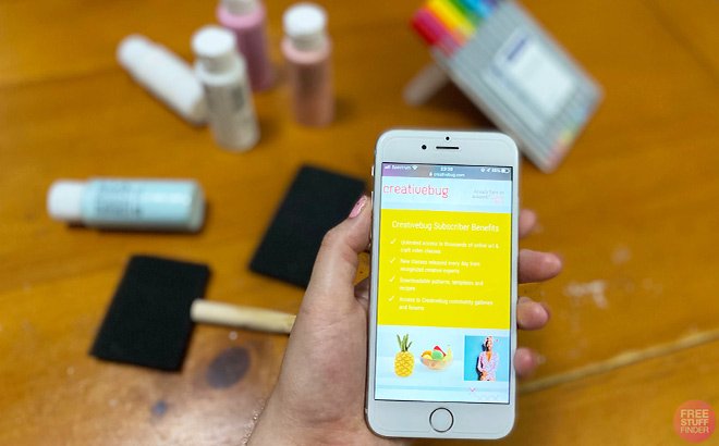 A Person Holding a Phone with Creativebug on the Background