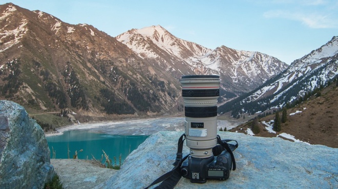 A Professional Camera on a Rock with a Picturesque Mountain Landscape in the Background