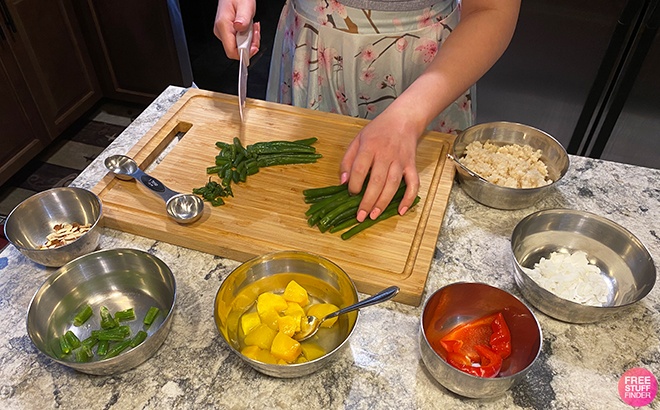 Person Cutting Up Asparagus Next to Other Ingredients Spread Around the Cutting Board on a Kitchen Counter