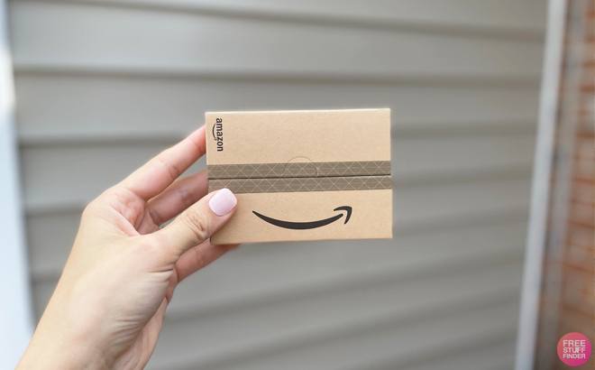Hand Holding an Amazon Gift Card in a Brown Case in front of a Garage Door