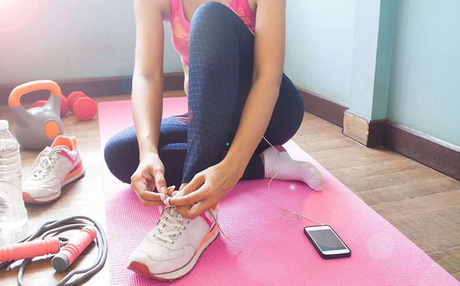 A Person in Workout Clothes Tying Their Shoelaces on an Exercise Mat