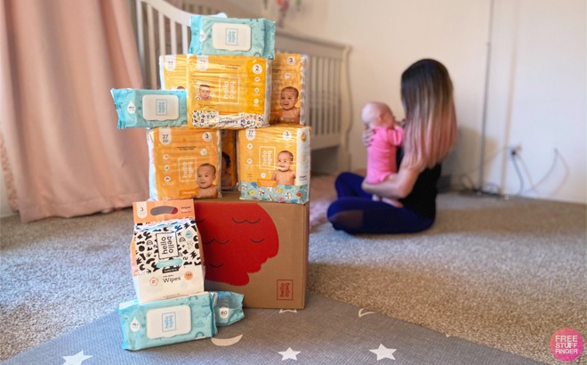 Hello Bello Diaper Bundle on a Floor with a Person Hodling a Baby in the Background