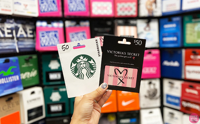 Hand Holding Starbucks and Victoria's Secret Gift Cards in fronts of Gift Cards