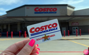 Person Holding Costco Gold Star Member Card in Front of Costco