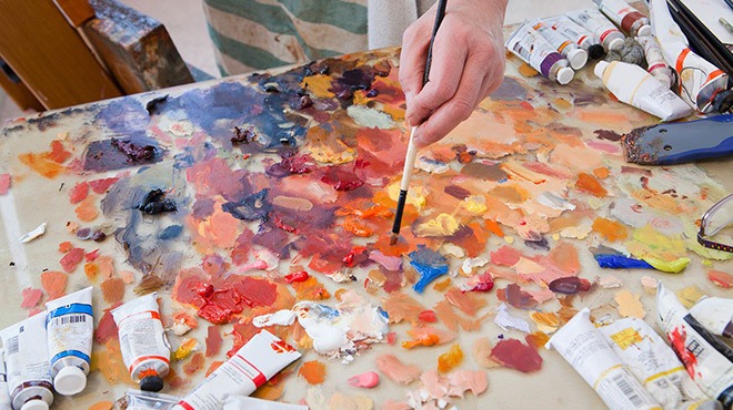 A Hand Holding a Brush and Painter's Palette with Multiple Colors on It
