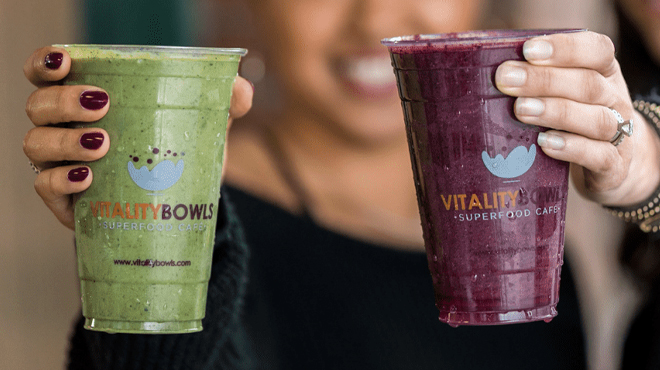 Hand holding two Vitality Bowl Smoothies