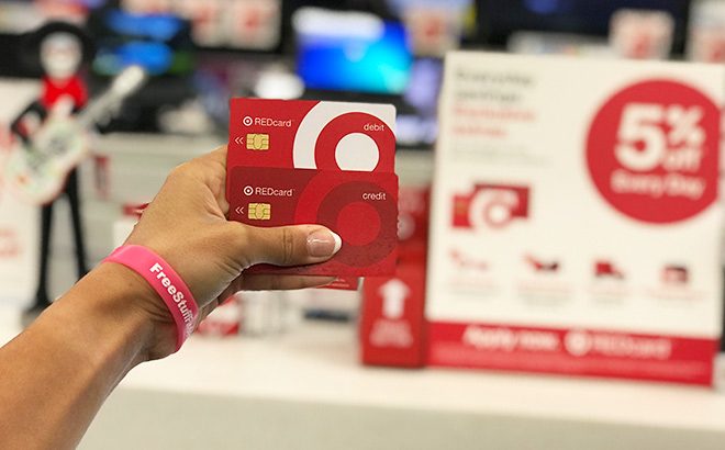 Woman's Hand Holding Target Debit and Credit Redcard in Front of Redcard Sign