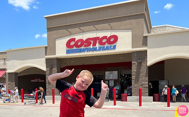 A Child Standing in Front of Costco and Pointing to the Costco Sign Above the Entrance to the Store
