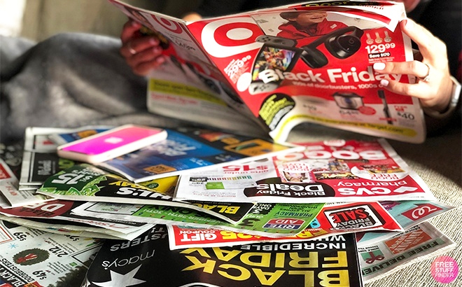 A Person Holding a Target Black Friday Brochure with Other Retailer's Brochures on the Table