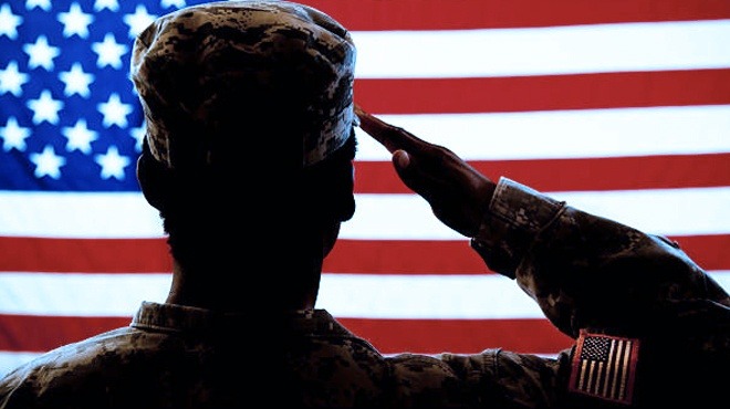 A Photo of a Person in Military Uniform Looking at the USA Flag and Saluting It