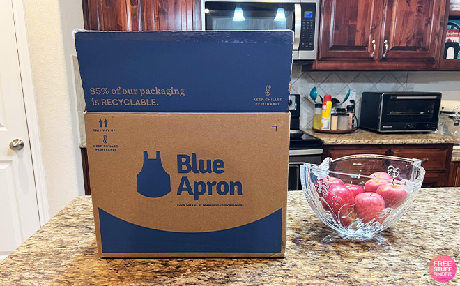Blue Apron Box next to a Bowl of Apples on a Kitchen Countertop