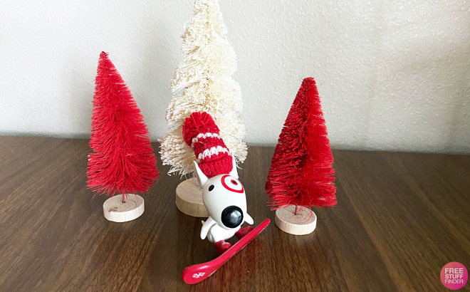 Bullseye Riding Snowboard Christmas Tree Ornament infornt of tiny Christmas Trees