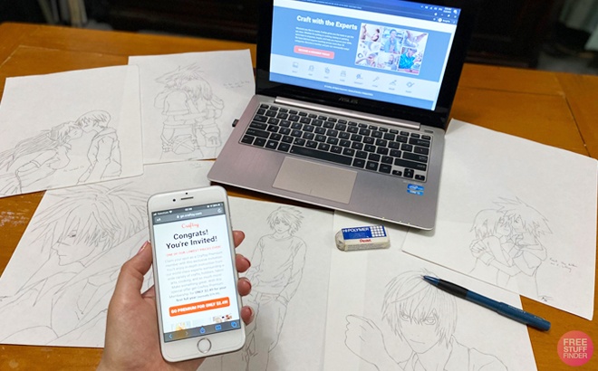 A Person Holding a Phone next to a Laptop and Drawings