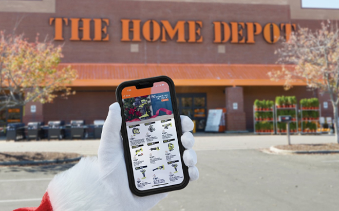 Hand Holding a Phone Showing Home Depot Black Friday 2023 Sales in Front of the Home Depot Store