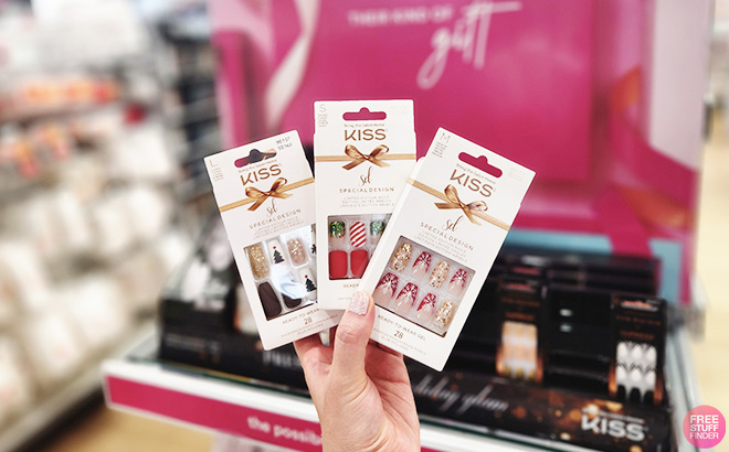 A Hand Holding Three Boxes of Kiss Press-on Nails at a Store