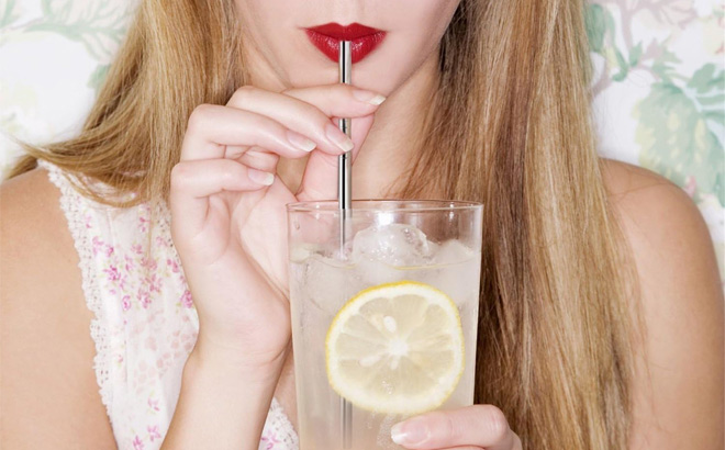 A Person Using a Stainless Steel Straw to Drink Water from a Glass