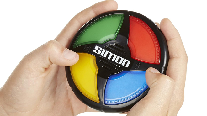 A child holding a Hasbro Gaming Simon Micro Series Game