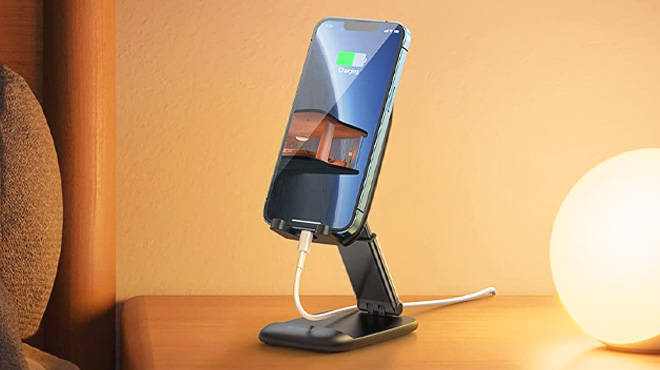 A Foldable Black Phone Stand Holding a Mobile Phone on a Tabletop