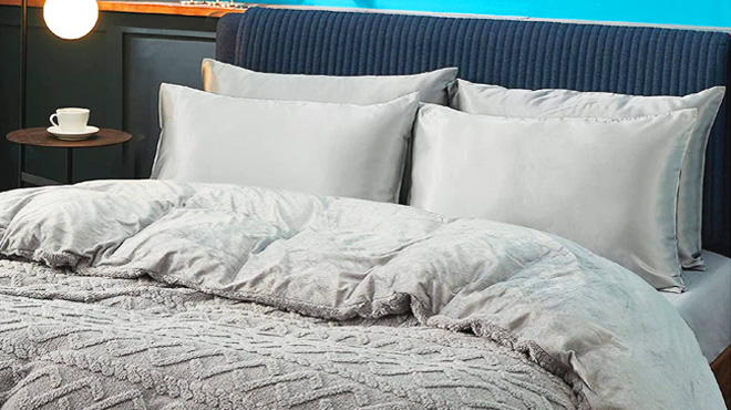 A Bed with Four Pillows and a Comforter in a Silver Gray Color