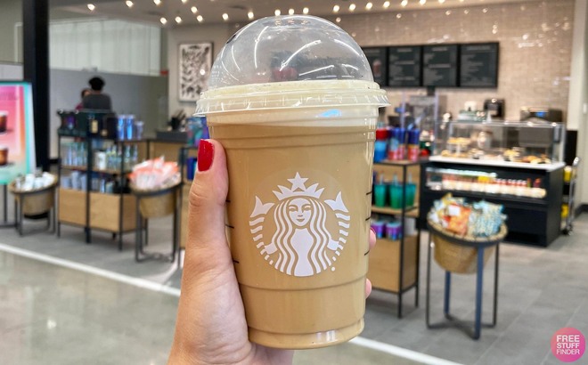 Hand Holding Starbucks latte drink inside a Target store