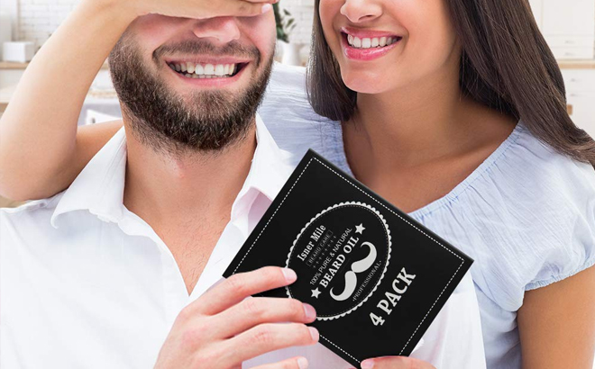 A Person Holding Their Hand over Another Person's Eyes Wile that Person Is Holding a Beard Oil Box