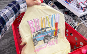 A Hand Holding Ford Bronco Womens Oversized Graphic Shirt in Yellow Color at Target