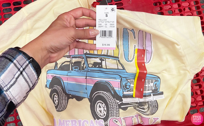 A Hand Holding a Price Tag of Ford Bronco Womens Oversized Graphic Shirt in Yellow Color at Target