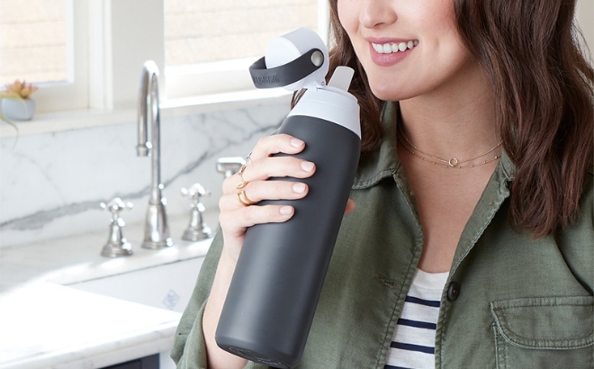 A Woman Holding the Brita Filtering 20 Ounce Water Bottle in Carbon Gray