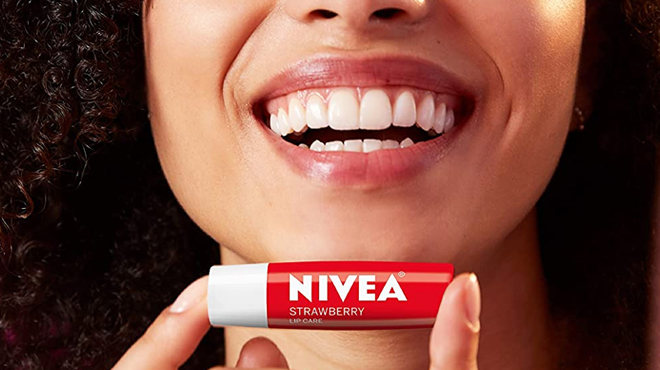 A Woman Smiling Holding a Nivea Strawberry Lip Balm