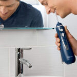 A amn brushing with Waterpik Cordless Water Flosser in blue