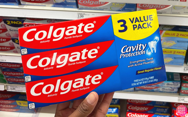 Woman Holding a Colgate Cavity Protection Toothpaste 3-Pack at Target store