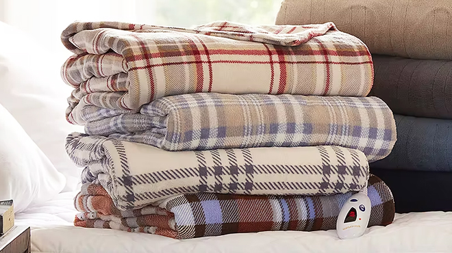 Four Biddeford Heated Throws in Plaid on a Bed