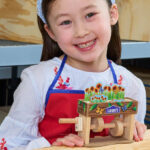 Girl Smilling and Holding a Spring Popup Flower Box from Lowes Kids Workshop