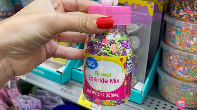 Hand Holding a Great Value Flower Sprinkles Mix if Front of the Store Shelf Hand Holding a Great Value Flower Sprinkles Mix if Front of the Store Shelf