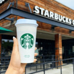 Hand Holding Starbucks Drink in Front of Starbucks Store