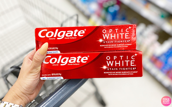 Hand Holding Two Colgate Stain Fighter Toothpastes on Cart at Walgreens