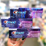 Hand holding three Crest 3D White Toothpastes