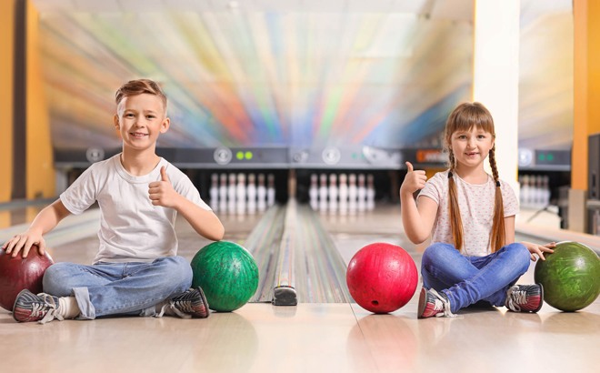 Kids Bowl Free With a Boy and a Girl Posing with Bowling Balls
