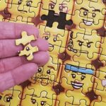 LEGO Minifigure Faces 1000 Piece Jigsaw Puzzle with a Piece in Hand