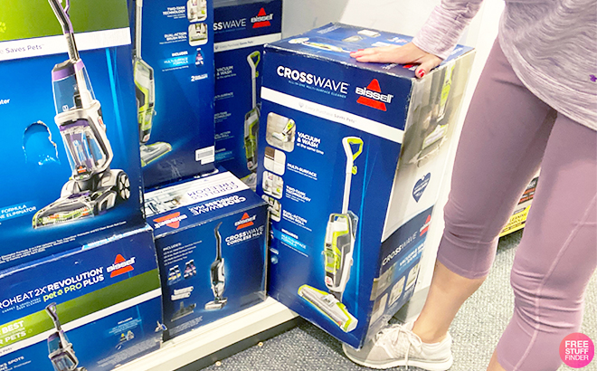 Person Holding Bissell CrossWave Bagless Stick Vacuum in a Store Aisle