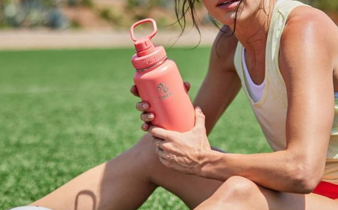 a Person Holding a Takeya Pink Actives Insulated Stainless Steel Water Bottle with Spout Lid