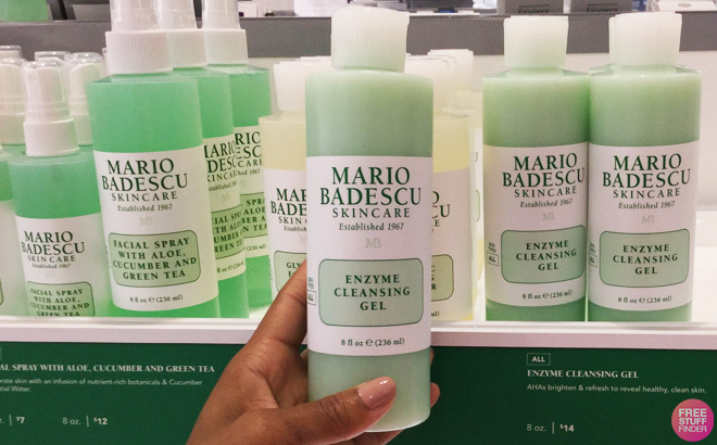 Hand Holding Mario Badescu Enzyme Cleansing Gel in front of teh Store Shelf
