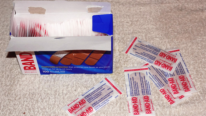 A 100 Count Pack of Band Aid Adhesive Bandages on the Carpet