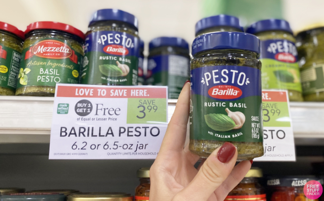 A Hand Holding a Barilla Pesto Sauce Beside Its Price Tag