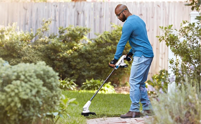 A Man Using the Hart 20 Volt Cordless 10 inch String Trimmer in the Garden
