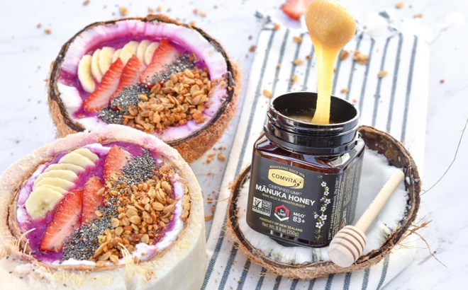 Comvita UMF 5 Raw Manuka Honey on a Table with Coconuts and Acai Bowls
